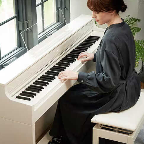 A Casio AP-S450 in White finish with a woman playing it in a living room.